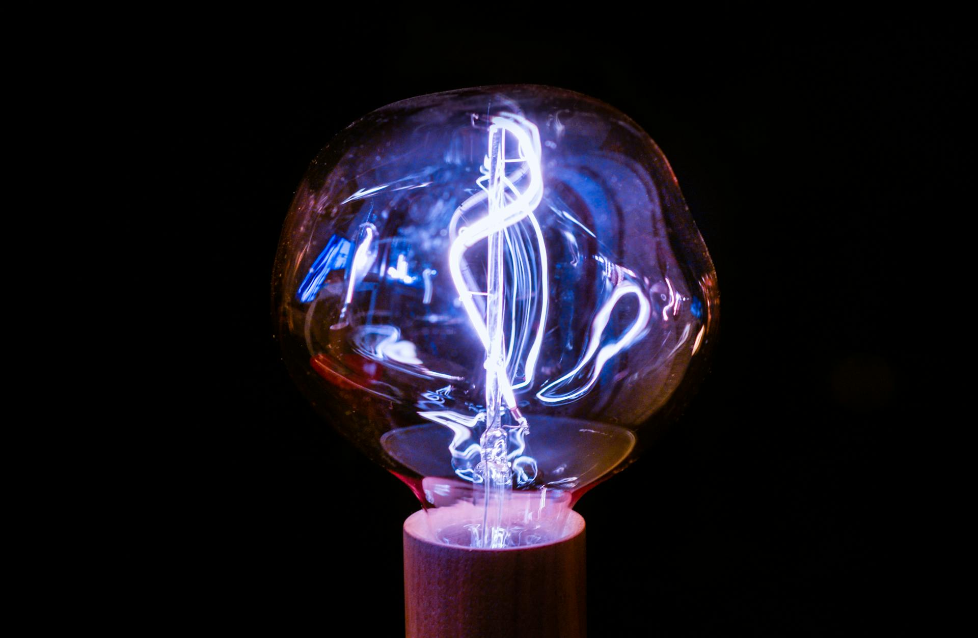 Misshapen lightbulb's light reflects in waves of purple and blue hues.