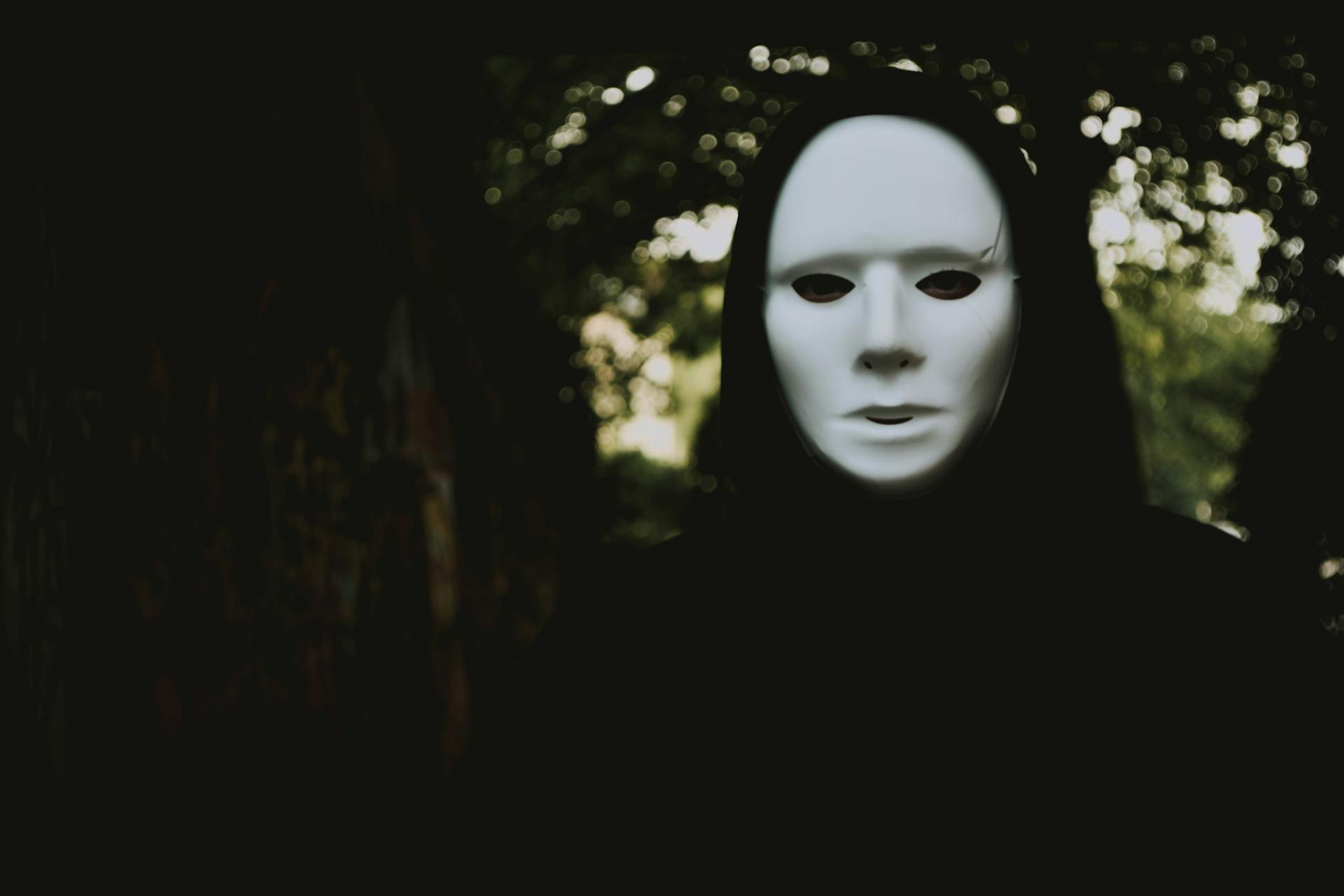 Person in black wearing a white featureless mask.